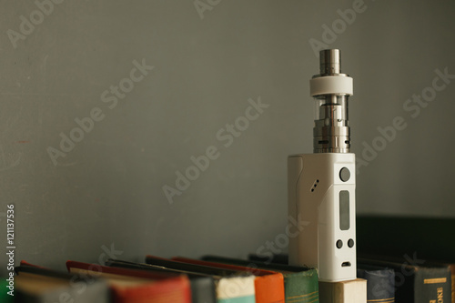 E-cigarette or vaping device on a neutral background. Next to them are the books