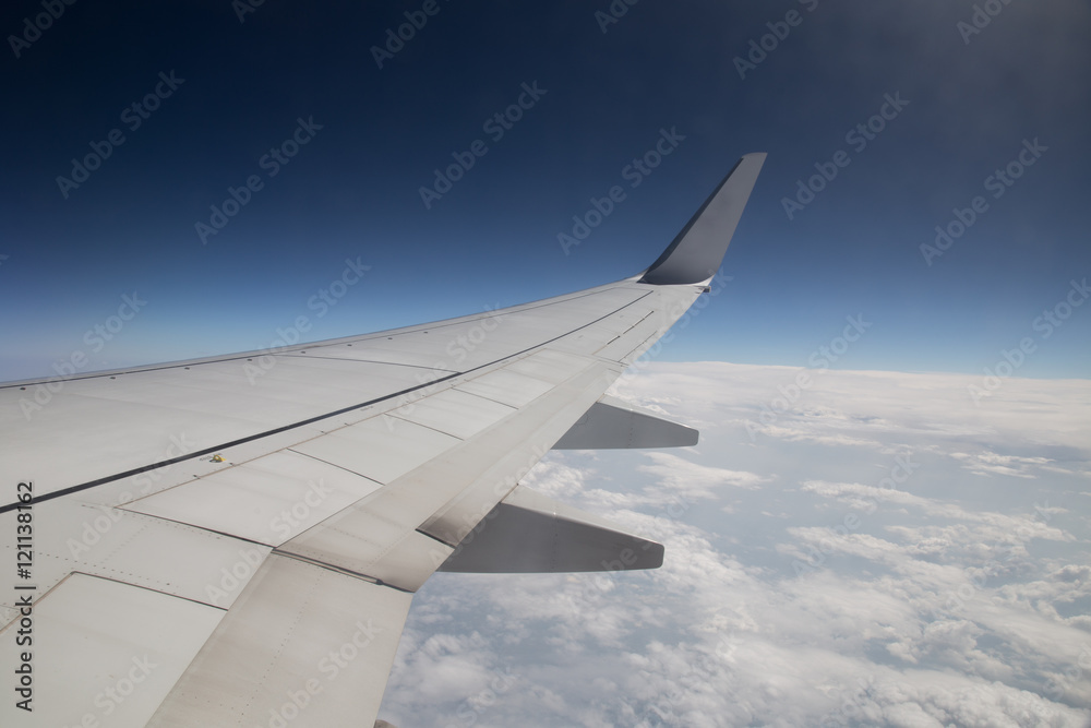 Wing of an airplane flying above the clouds. people look at the sky from the window of the plane, using air transport to travel. back light sun beam Wing of an airplane flying above the clouds. people look at the sky from the window of the plane, using air transport to travel. back light sun beam