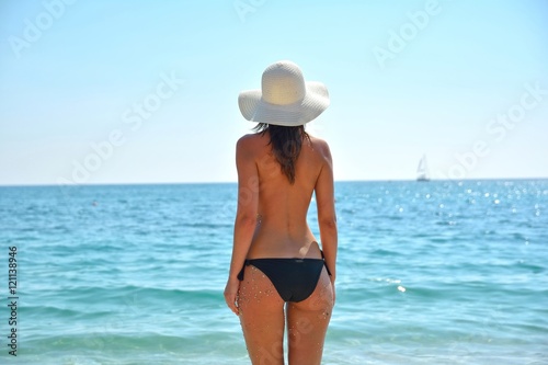 Back view of long haired young woman on tropical beach
