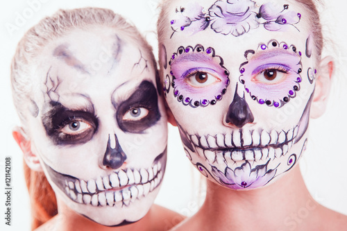 Two girls with Halloween face art on white background © kanashkin