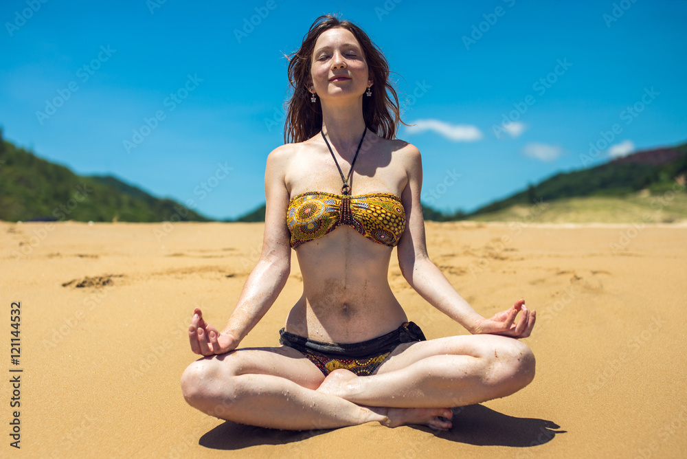 young woman meditating on beach