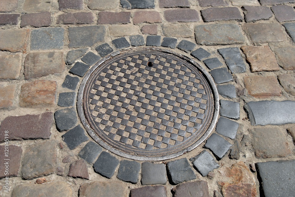 Sewer manhole cover old cobblestone street