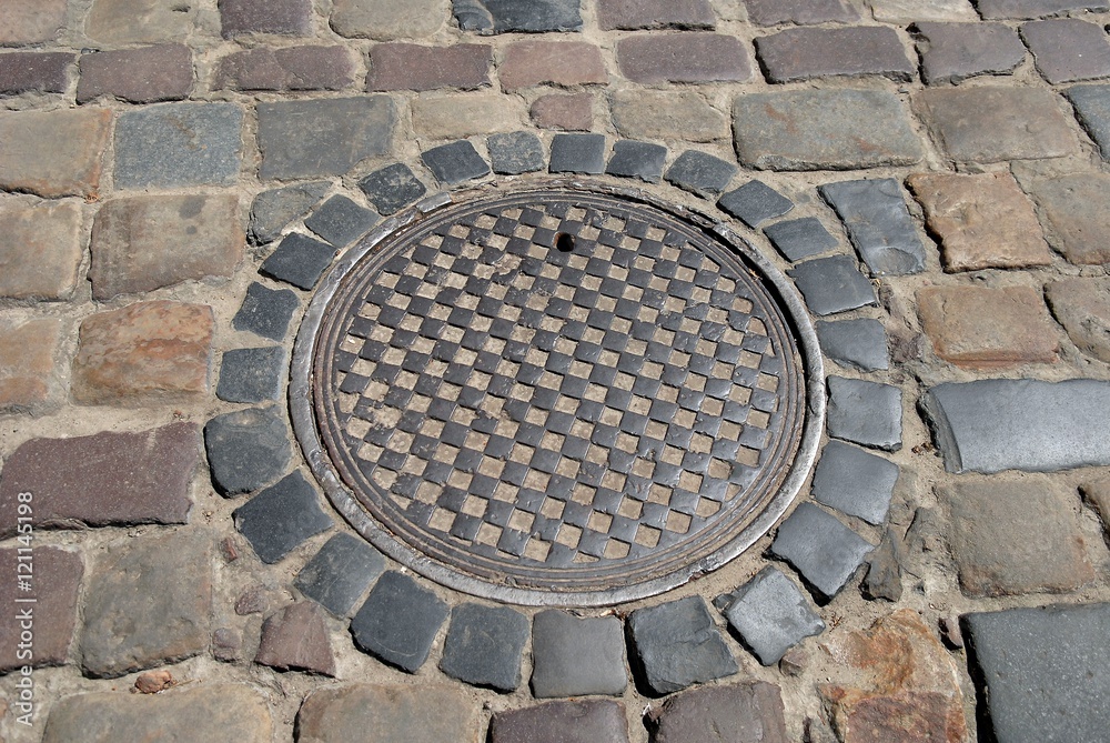 Sewer manhole cover old cobblestone street Sewer manhole cover old cobblestone street