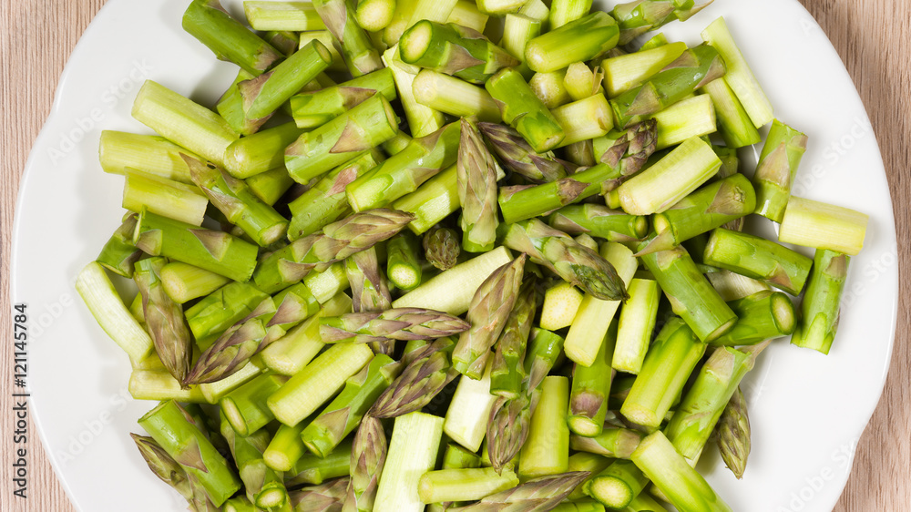Close up on sliced pieces of green asparagus on a white plate Close up on sliced pieces of green asparagus on a white plate