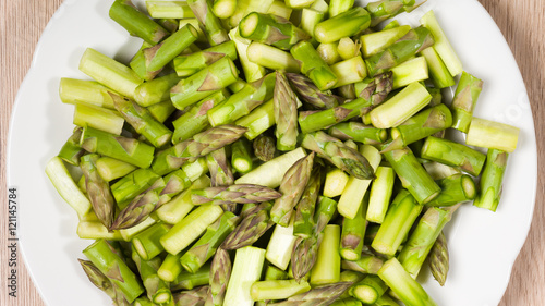 Close up on sliced pieces of green asparagus on a white plate