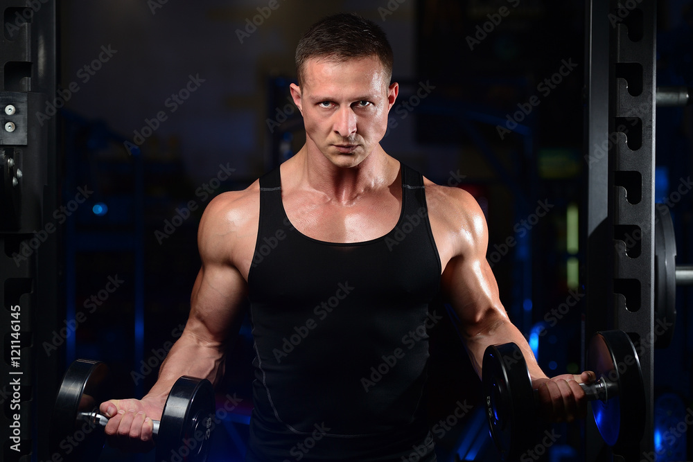 Handsome athletic fitness man posing and trains in the gym. Handsome athletic fitness man posing and trains in the gym.