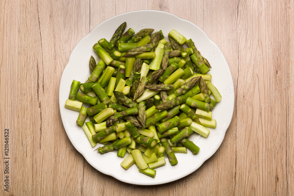 Close up on sliced pieces of green asparagus on a white plate Close up on sliced pieces of green asparagus on a white plate