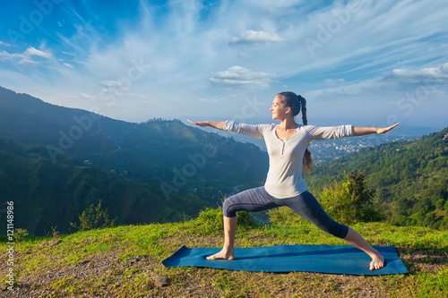 Woman doing yoga asana Virabhadrasana 2 - Warrior pose outdoors