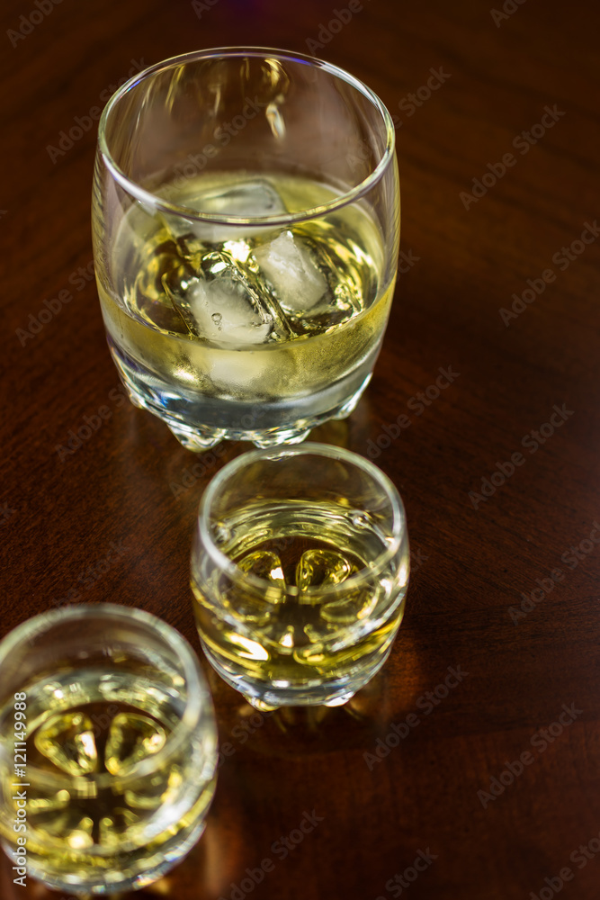 Two small glasses of whiskey and glass of whiskey with ice.