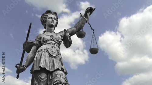 Statue of Lady Justice zooming out in front of moving clouds