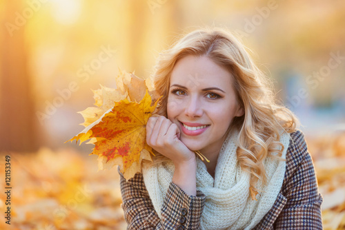 Woman in checked coat sitting in autumn park