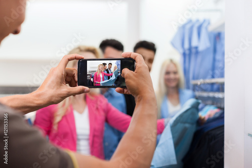 Man Taking Photo Of Young People Shopping, Happy Smiling Friends Two Couple Customers In Fashion Shop