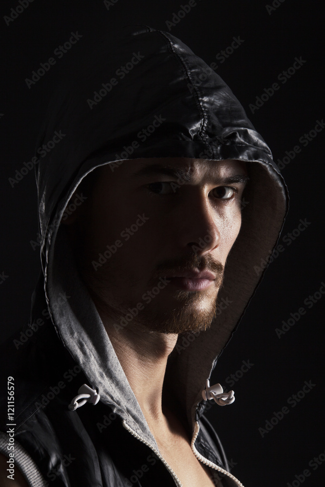 Close-up portrait of threatening gangster wearing a hood, representing the concept of danger Close-up portrait of threatening gangster wearing a hood, representing the concept of danger
