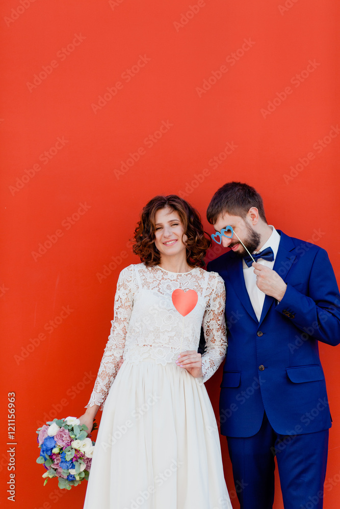 Bride and groom standing next to a red wall