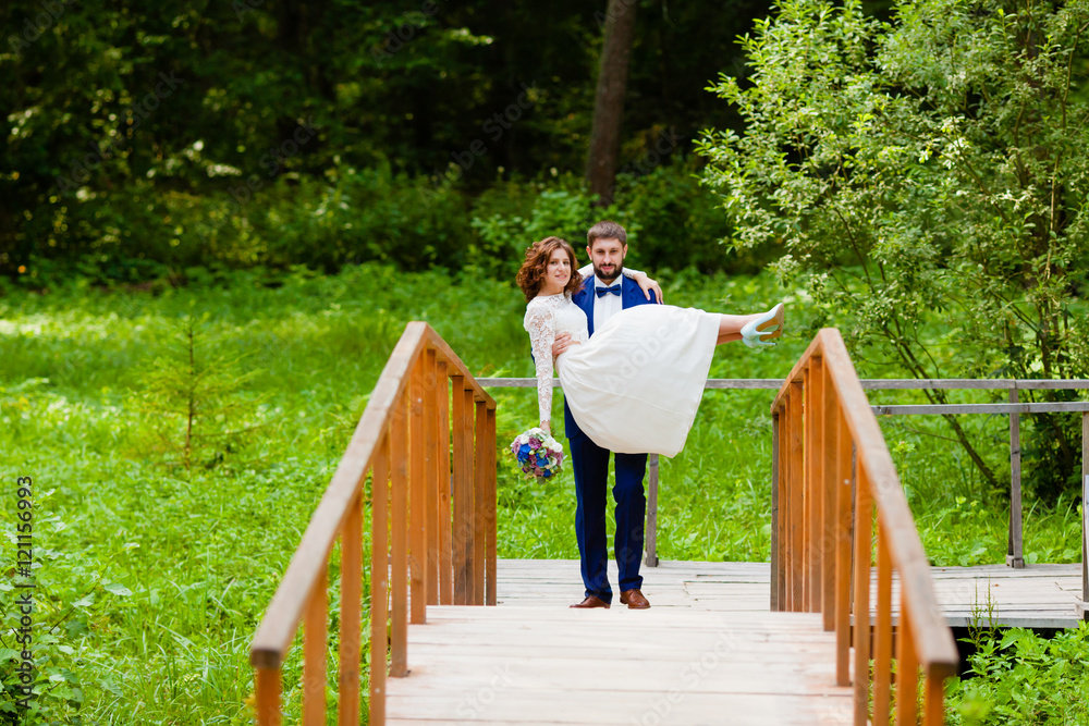 Bride and groom walking on a wooden bridge Bride and groom walking on a wooden bridge