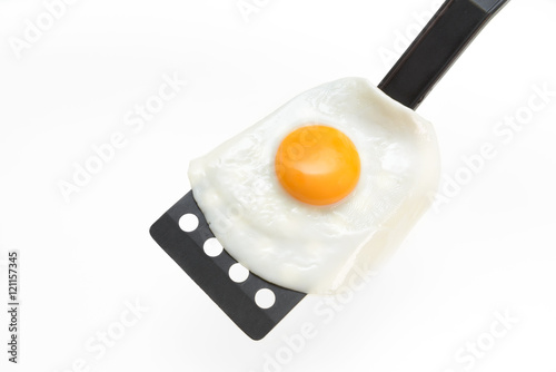 Fried egg on the spatula, ready to be served. White background.