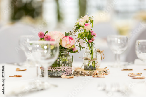 Gläser und Blumendeko auf gedecktem Tisch