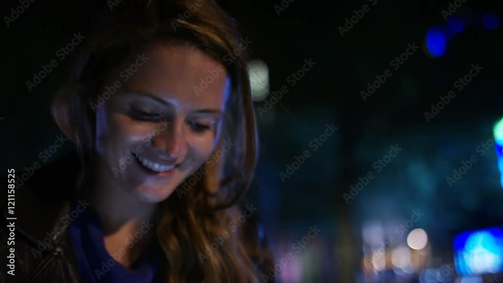 Attractive young woman using her tablet device in the city at night Attractive young woman using her tablet device in the city at night