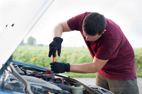 man repairing his car on the road