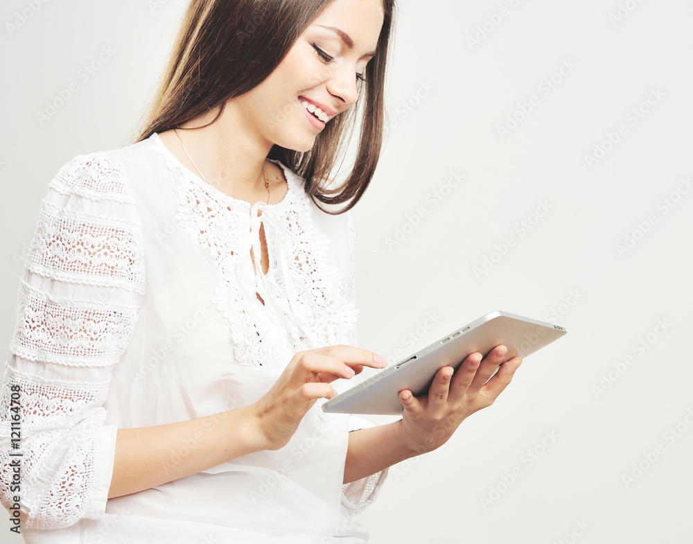 Portrait of a cheerful hipster woman pointing finger on tablet computer screen over gray background Portrait of a cheerful hipster woman pointing finger on tablet computer screen over gray background