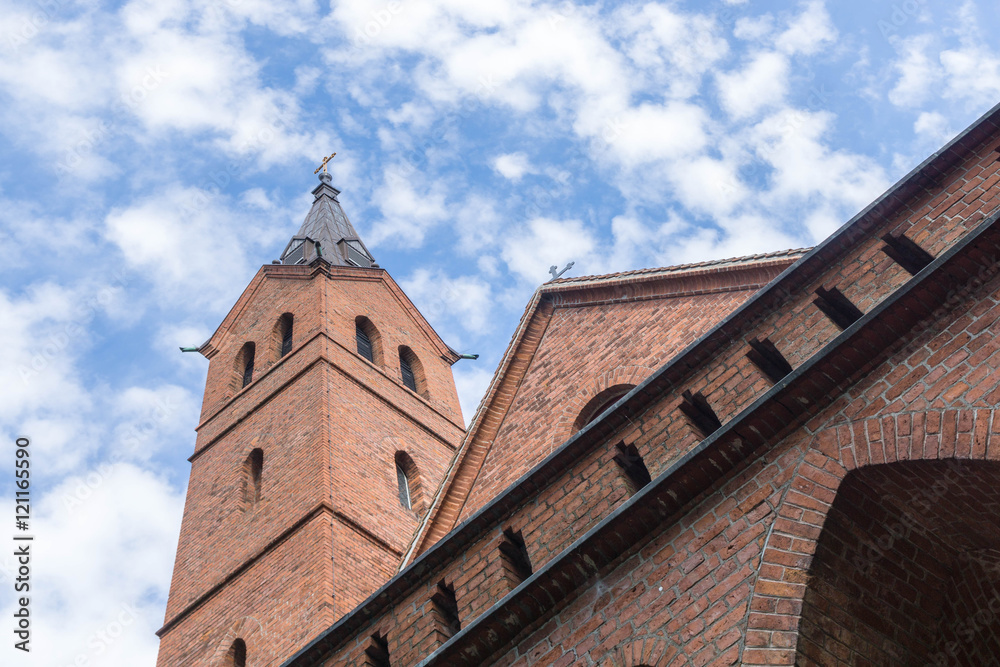 Alte Kirche mit Backsteinwänden vor wolkigem Himmel