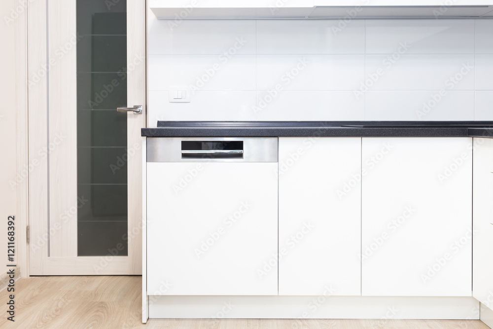 Build-in dishwasher in a white kitchen with black counter top. Stock Photo | Adobe Stock