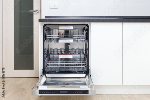 Build-in dishwasher with opened door in a white kitchen  photo