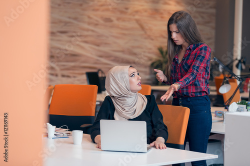 Worried arabic businesswoman wearing hijab receiving a notification from a colleague in her workplace at office photo