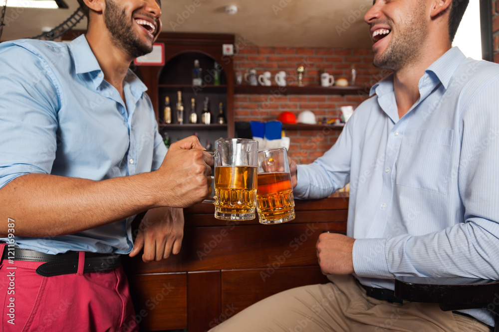 Two Man In Bar Clink Glasses Toasting Sit At Table, Drinking Beer Hold Mugs Close Up Two Man In Bar Clink Glasses Toasting Sit At Table, Drinking Beer Hold Mugs Close Up