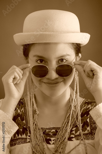 Beautiful hispanic model wearing light colored blouse, trendy sunglasses with matching hat, smiling posing for camera, studio background, black and white edition