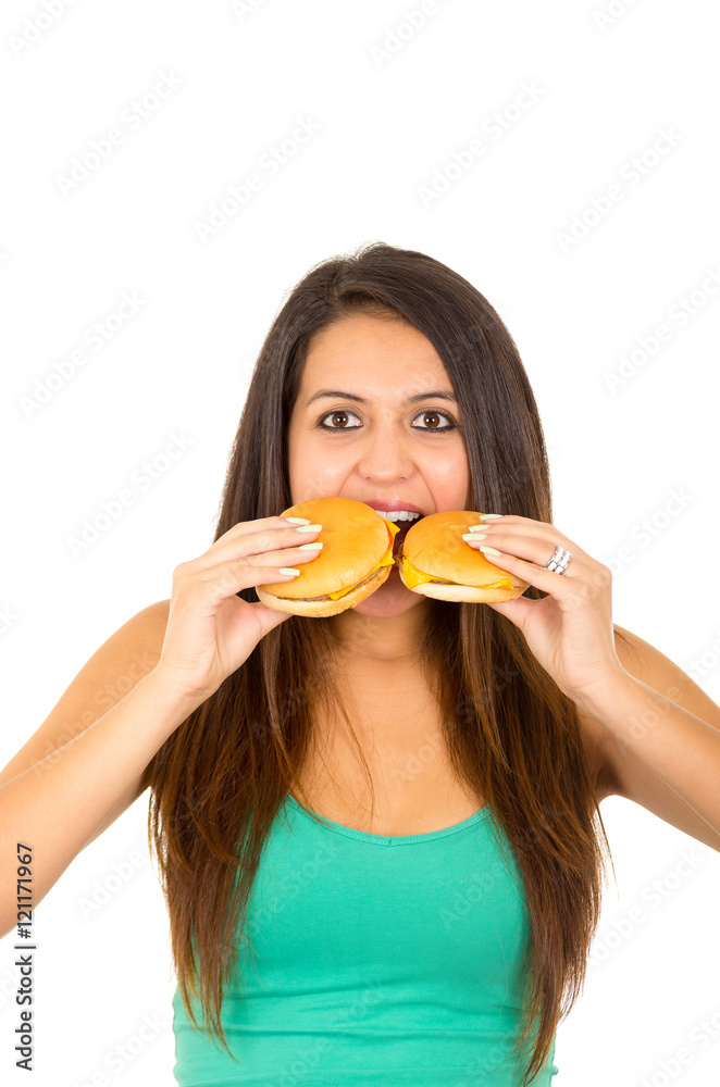 Beautiful young woman posing for camera holding two hamburgers next to mouth, smiling happily, white studio background Beautiful young woman posing for camera holding two hamburgers next to mouth, smiling happily, white studio background
