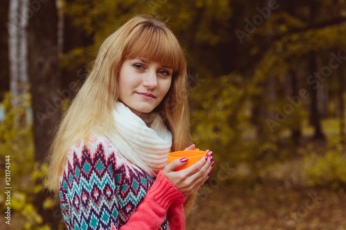 Fall concept - autumn woman drinking coffee in park