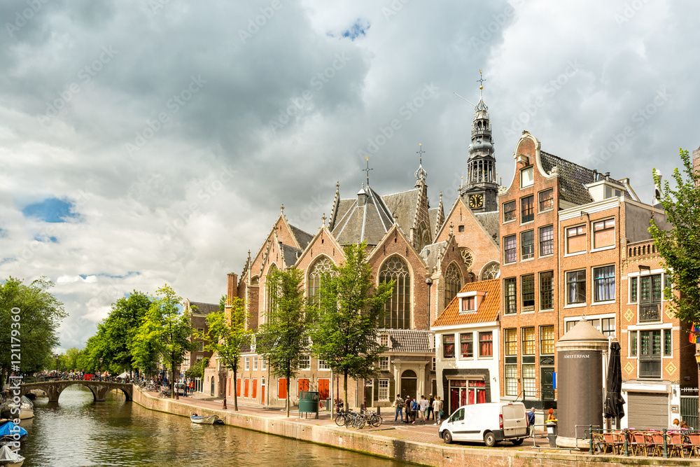 Fototapeta premium Amsterdam Red Light District canal with the Old Church (aka De Oude Kerk) among typical dutch houses, on a sunny summer morning