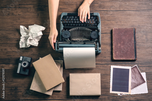 Εκτύπωση καμβά Woman hands working with retro typewriter, camera and photos on wooden backgroun