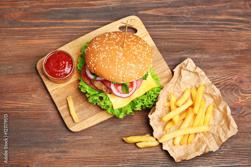Tasty cheeseburger with fries on wooden table