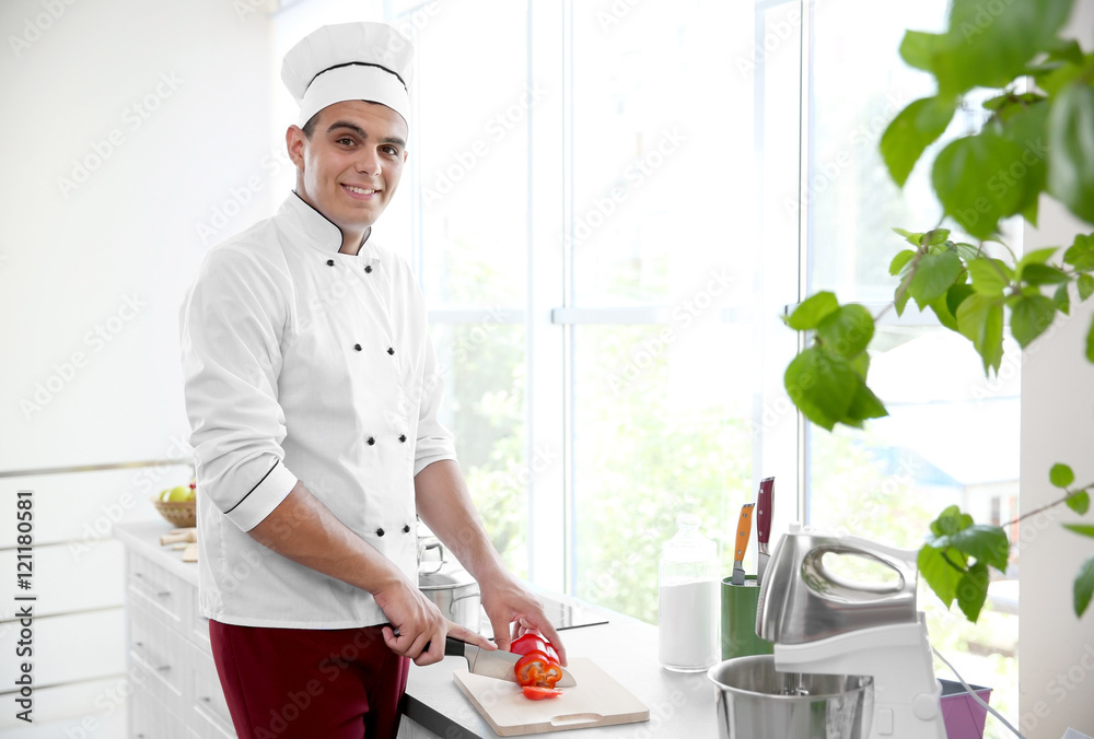 Young chef cook cutting fresh pepper in kitchen Young chef cook cutting fresh pepper in kitchen