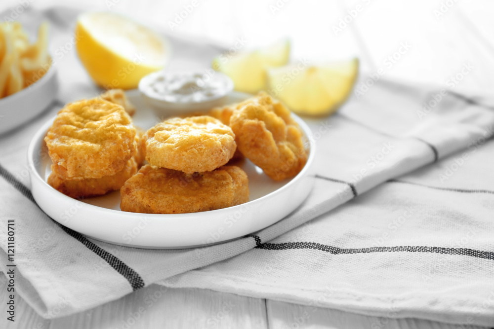 Tasty nuggets with sauce in plate and lemon on napkin Tasty nuggets with sauce in plate and lemon on napkin