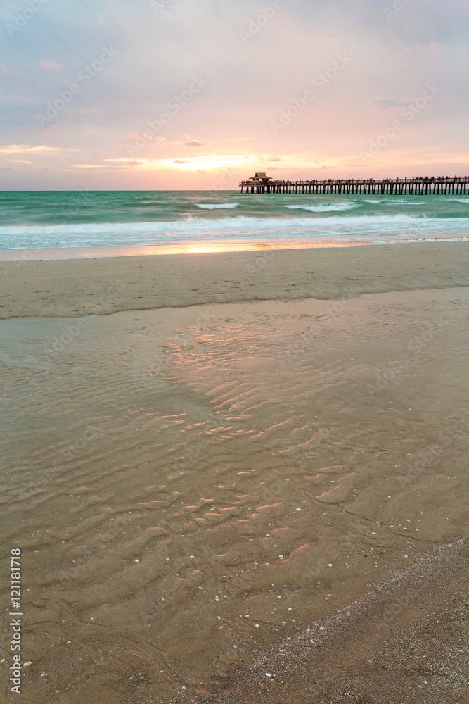 Obraz premium The sun goes down at the Naples Pier in the Gulf of Mexico, Southwest Florida, USA. Amazing landscape spot of the sun coming down at blue hour in this idyllic place for family vacation and relax.