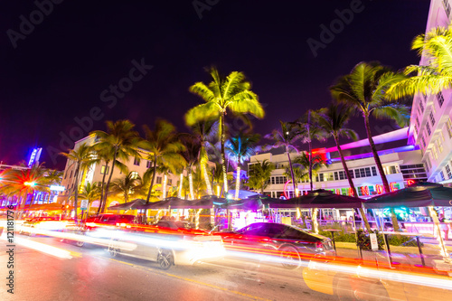 Ocean Drive scene at night with neon lights, palm trees, cars and people having fun, Miami beach.