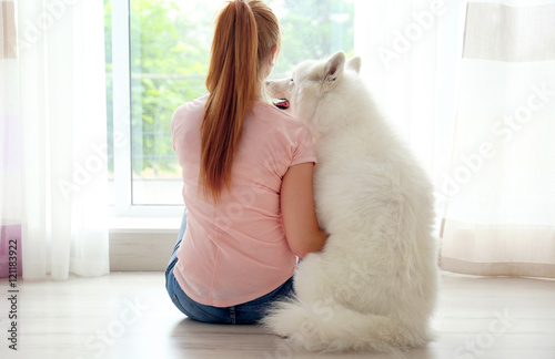 Girl and Samoyed dog huggin...