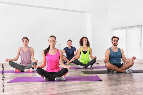 Group of people practicing yoga and meditating on mats