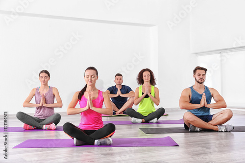 Group of people practicing yoga and meditating on mats