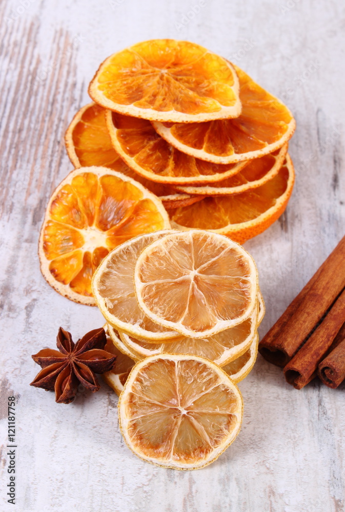 Slices of dried lemon, orange and spices on old wooden background