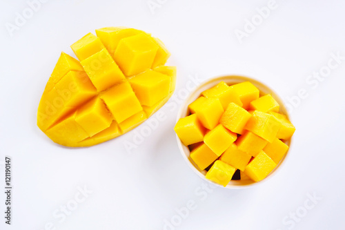 Top view of sliced ripe mango cubes in a white bowl on a white background.