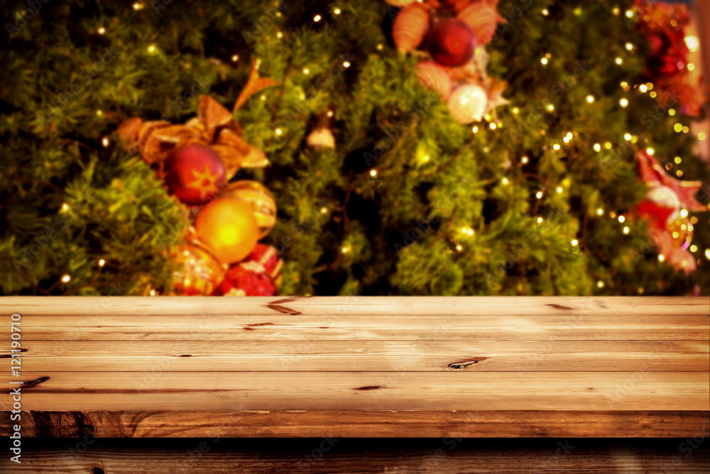 Christmas and New year background with empty dark wooden deck table over christmas tree and blurred light bokeh. Empty display for product montage. Rustic vintage Xmas background.
