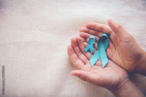 Hands holding Teal Ribbons, copy space toning background, Ovarian Cancer, cervical Cancer, Kidney Cancer awareness photo