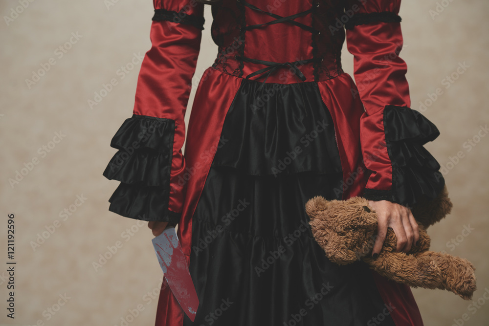 Girl in historical dress holding Teddy bear and bloody knife