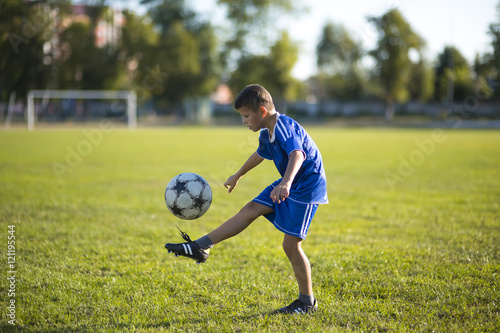 Boy kicking soccer ball on the football field