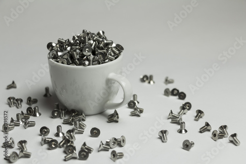Screws in a cup on white background. Industrial, decorative. Creative, original, unusual.