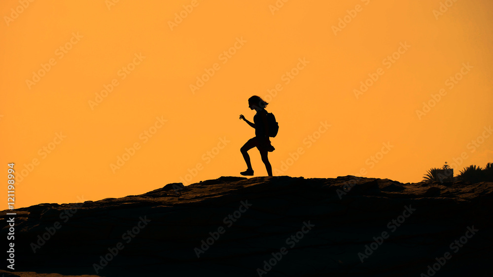 Silhouette of a girl walking on the mountain at sunset